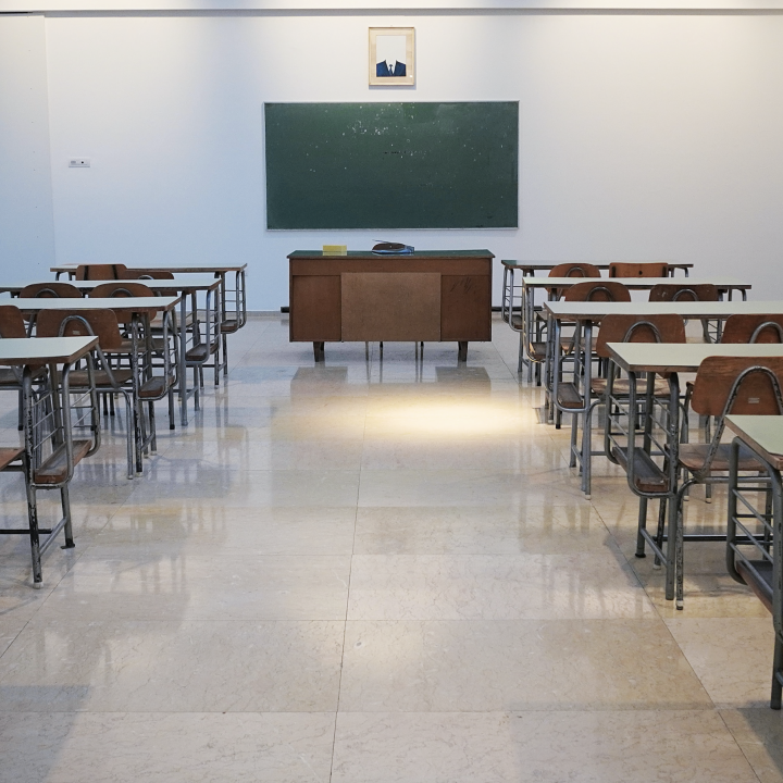 Empty classroom with green chalkboard on wall at end