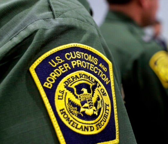 Yellow and blue CBP badge on green shirt