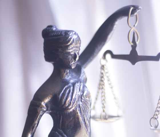 Metal statue of Lady Justice blindfolded and holding scales and a sword.